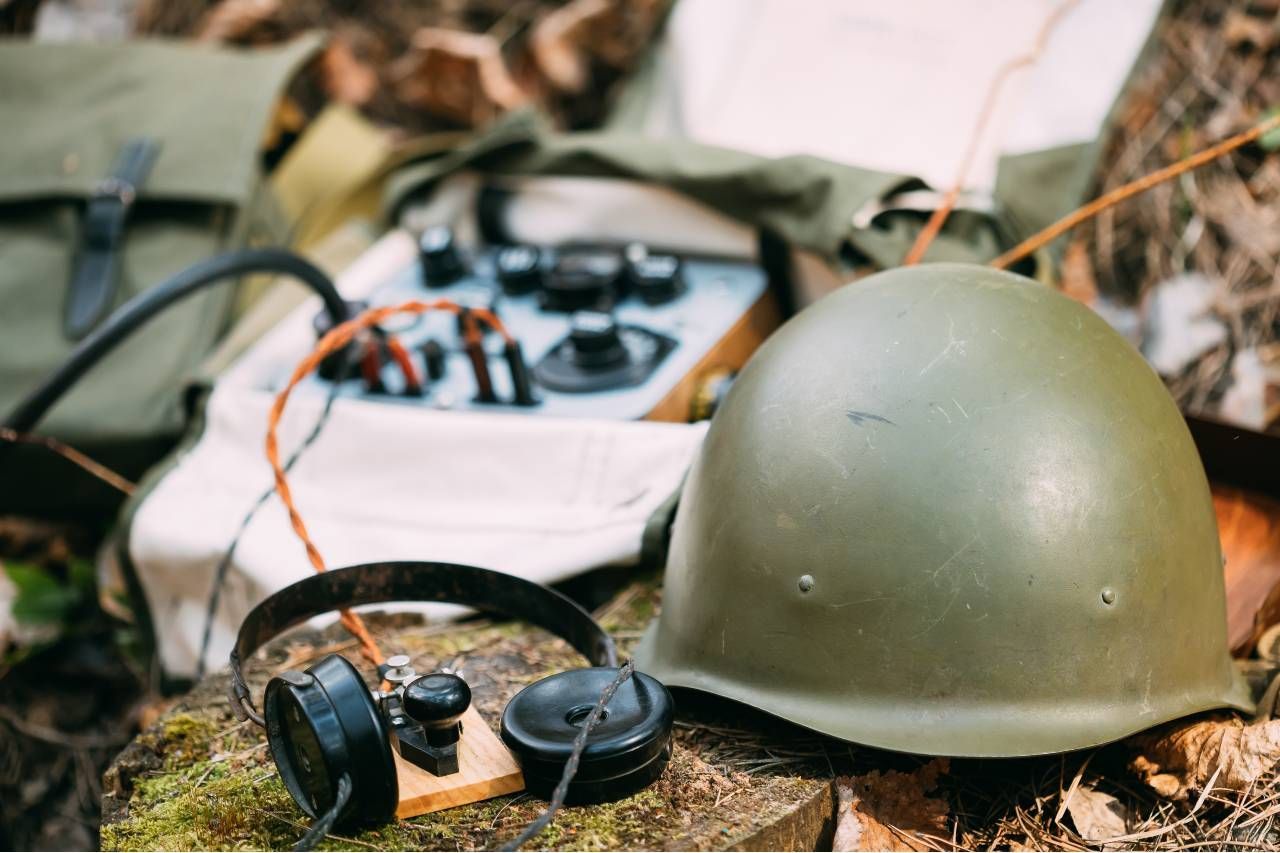 A helmet and headphones are sitting on a rock.