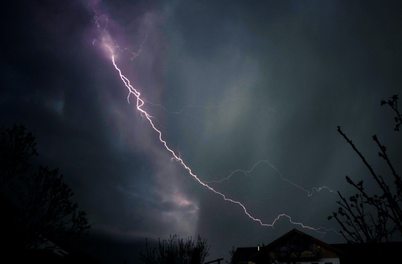 Lightning strikes in the night sky over a house