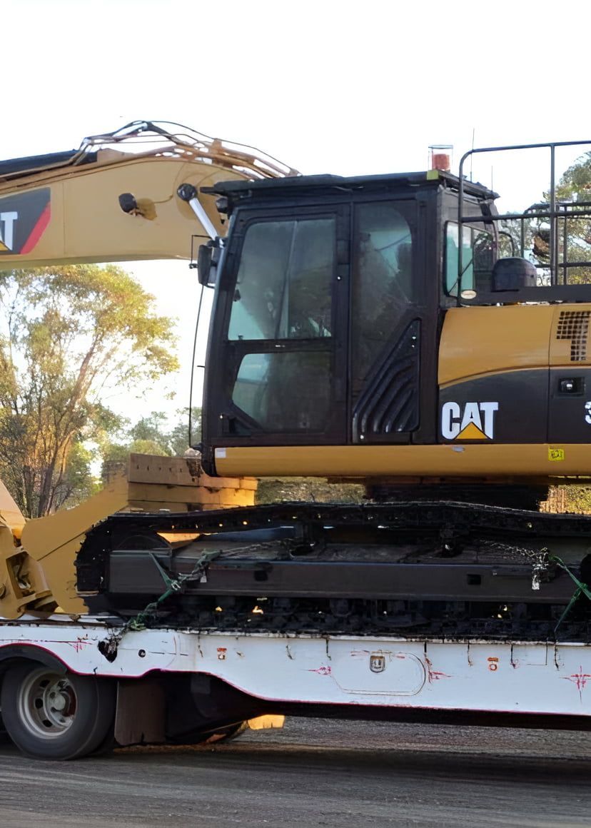 A Cat Excavator is Sitting on Top of a White Trailer —  A & B Mullins Excavations Pty Ltd in Burnett Heads, QLD