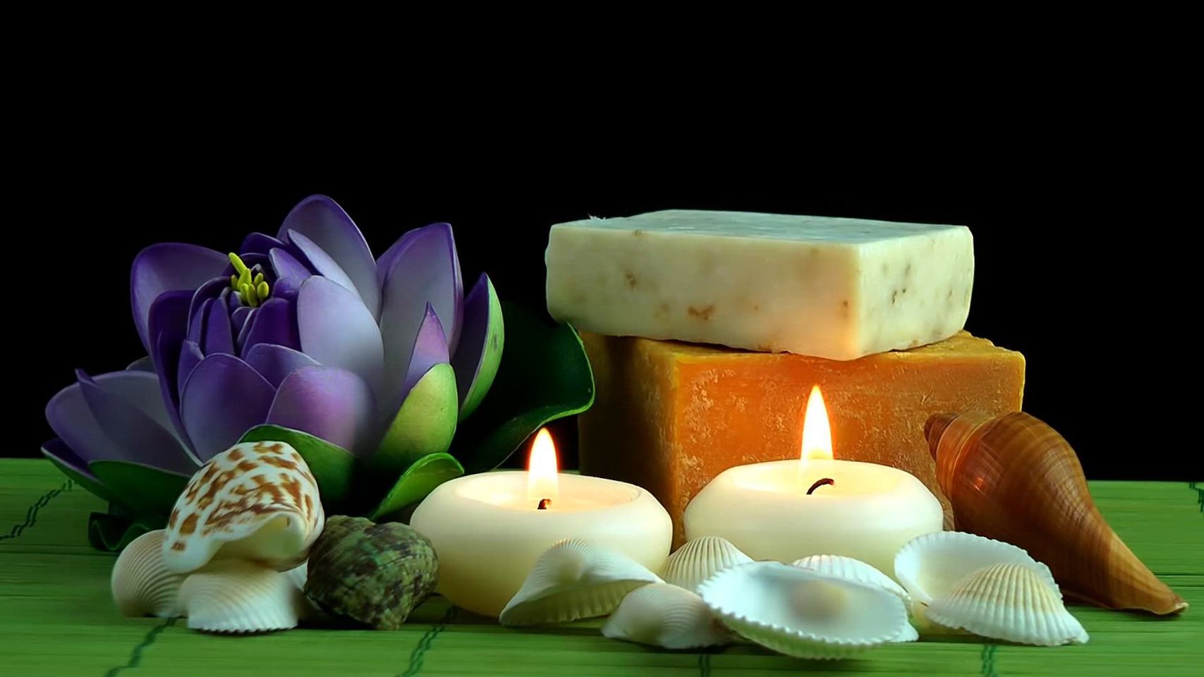 Candles , seashells , flowers and soap on a green mat