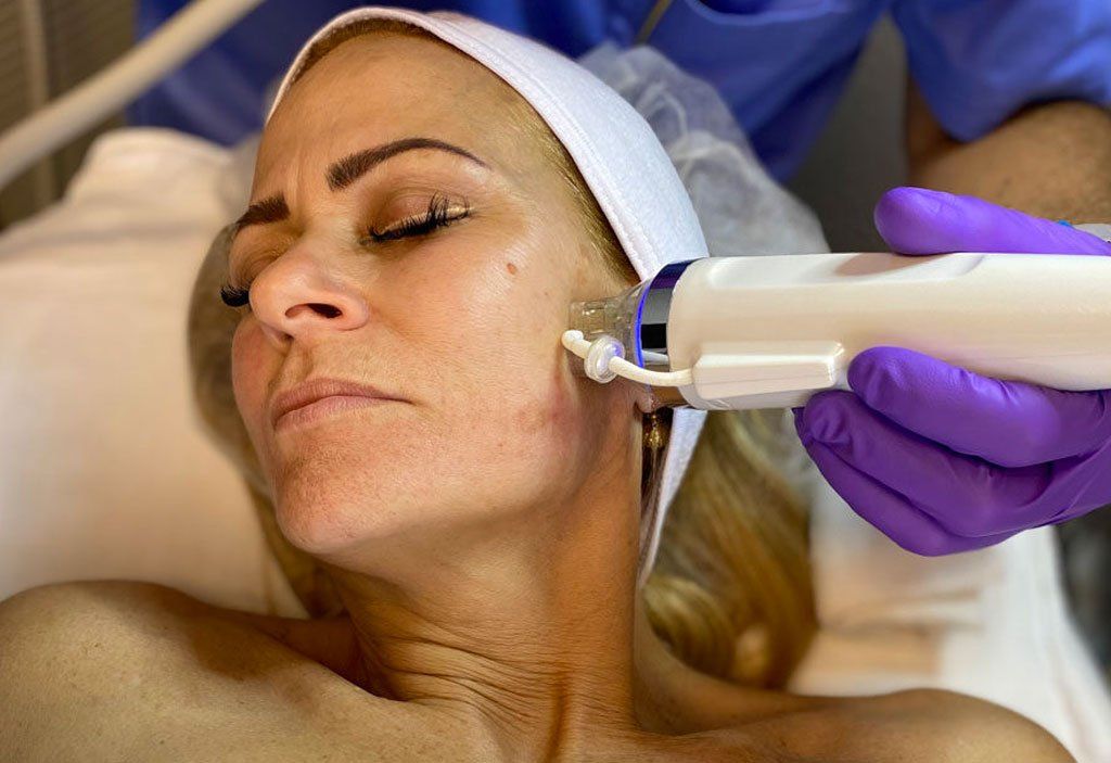 A woman is laying on a bed getting a facial treatment.