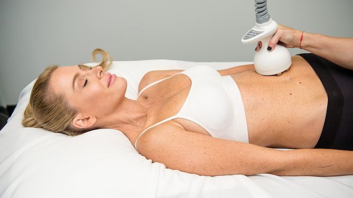 A woman is getting a cavitation treatment on her stomach.