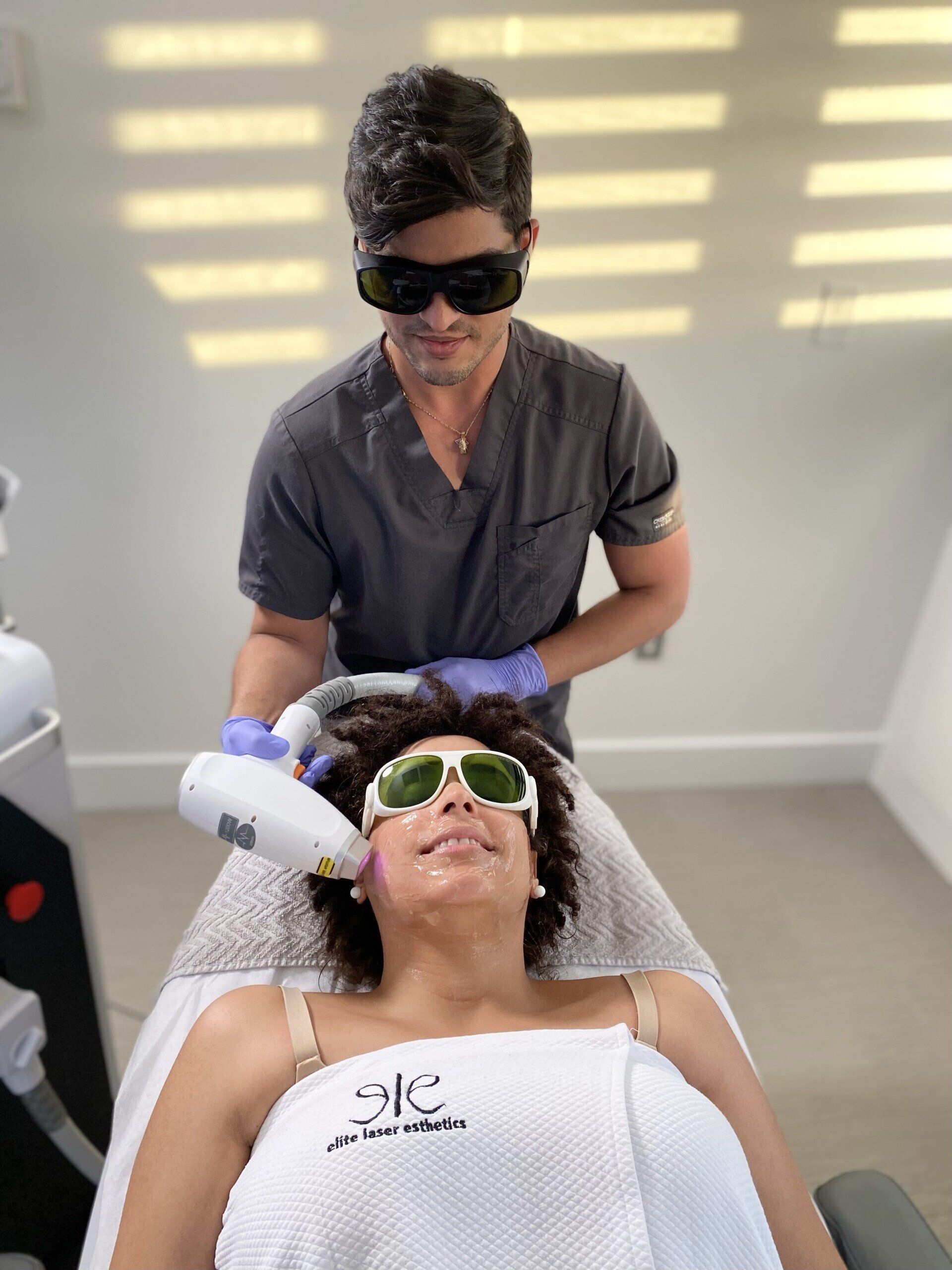 A man is giving a woman a laser treatment on her face.