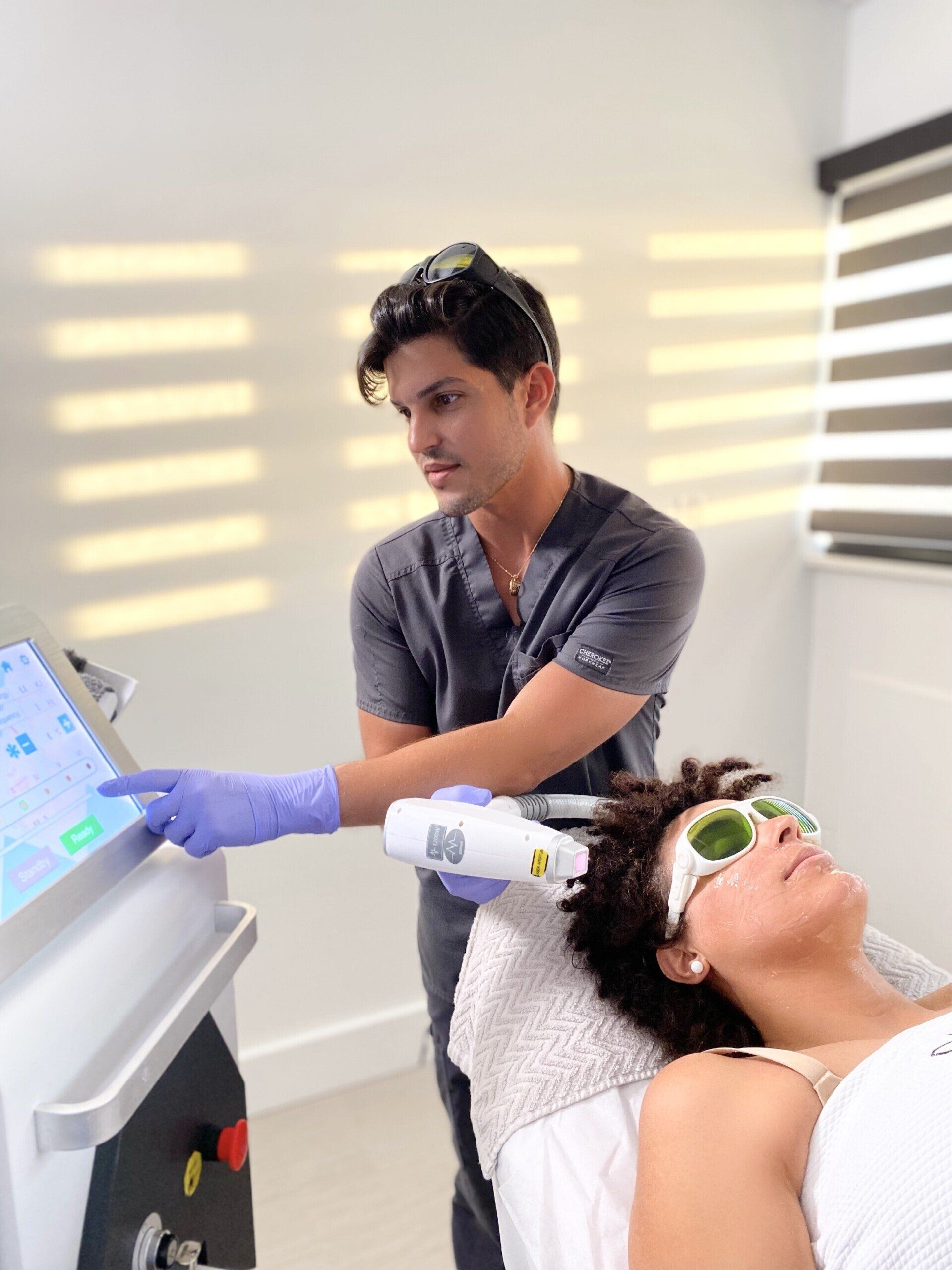 A man is using a laser on a woman 's face.