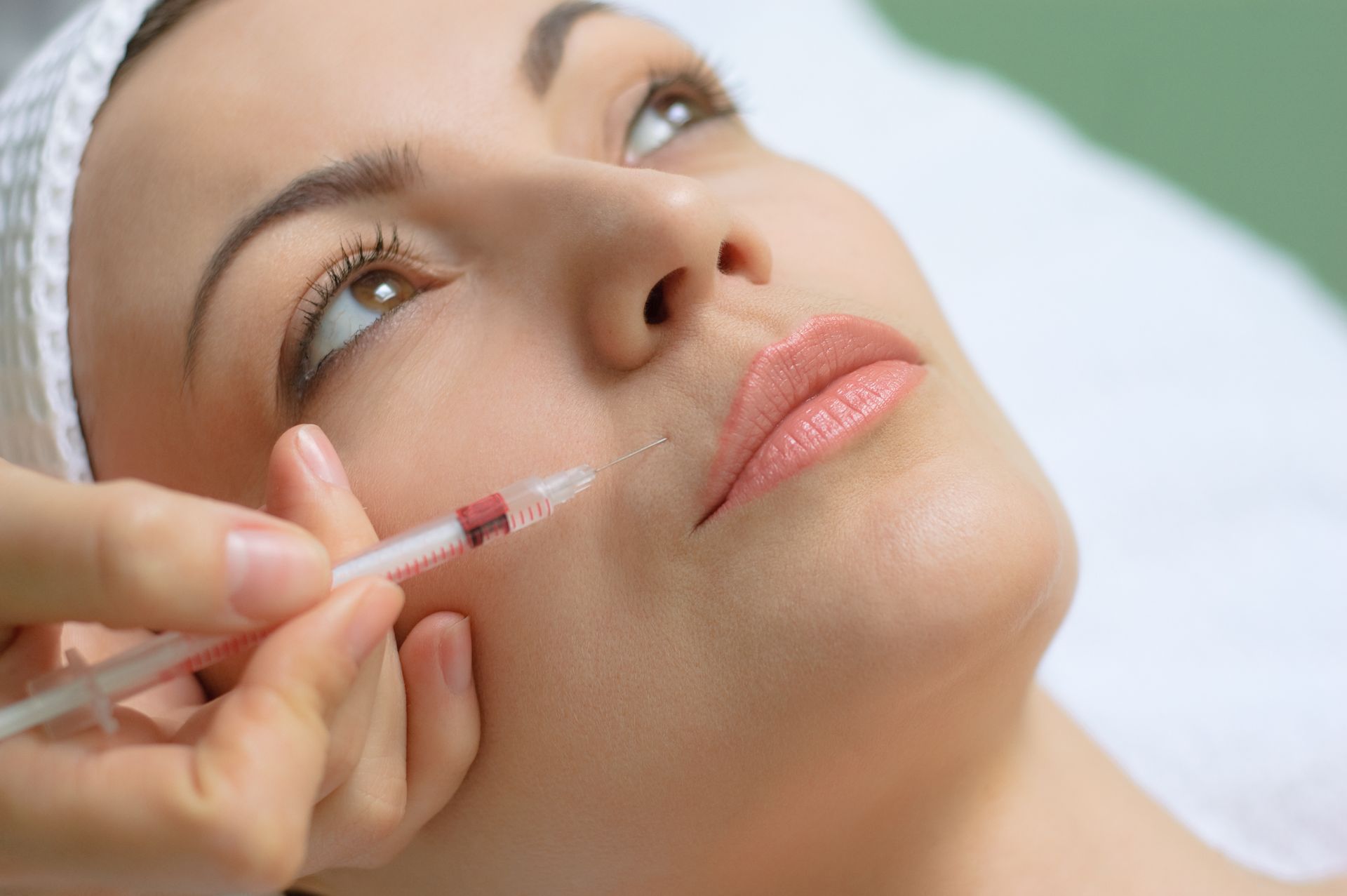 A woman is getting a botox injection in her face.