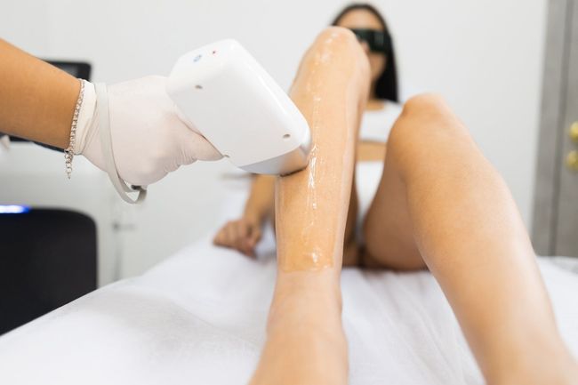 A woman is getting a laser hair removal treatment on her legs.