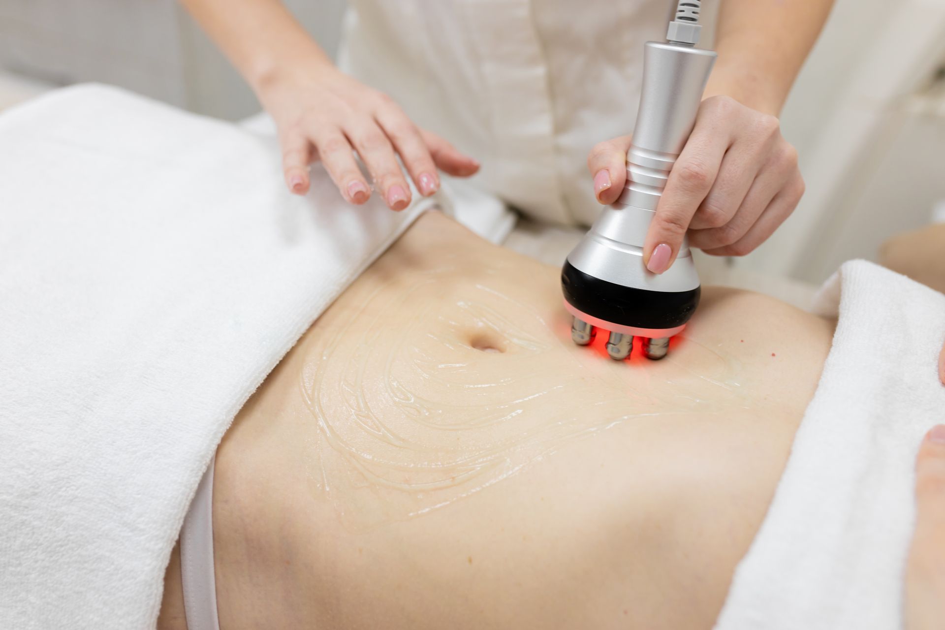 A woman is getting a cavitation treatment on her stomach.