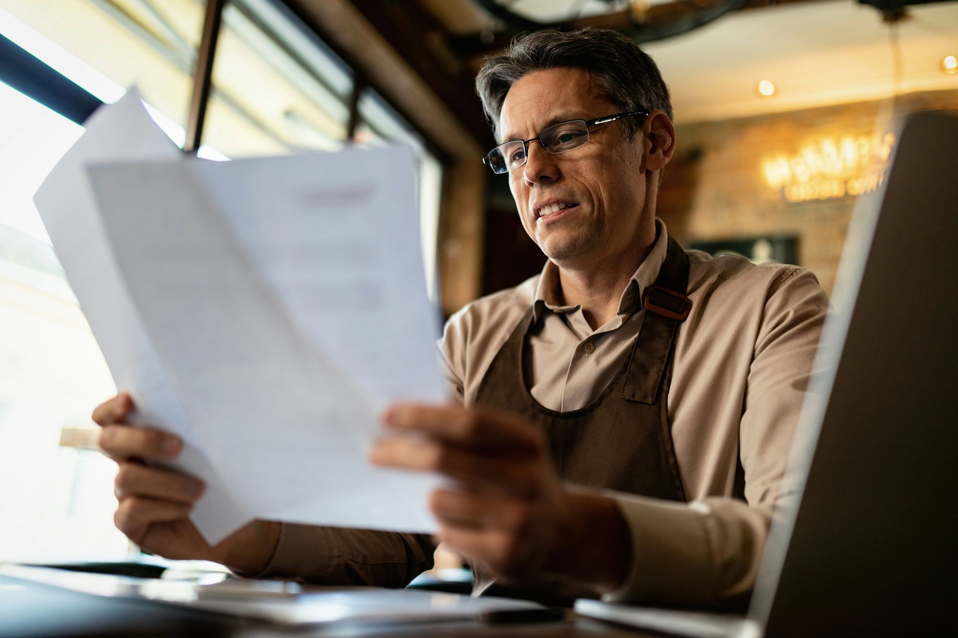 A man is sitting at a table looking at a piece of paper.