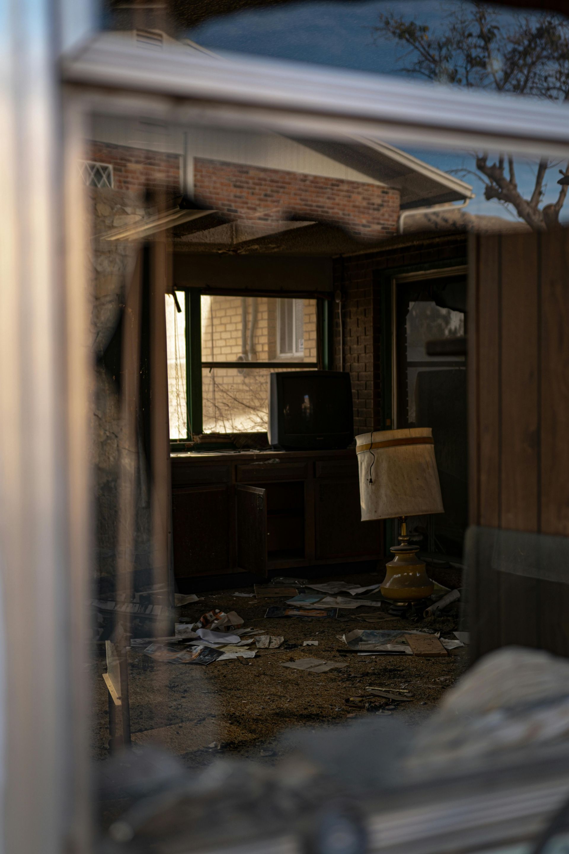 A room in an abandoned house with a broken window and a lamp.