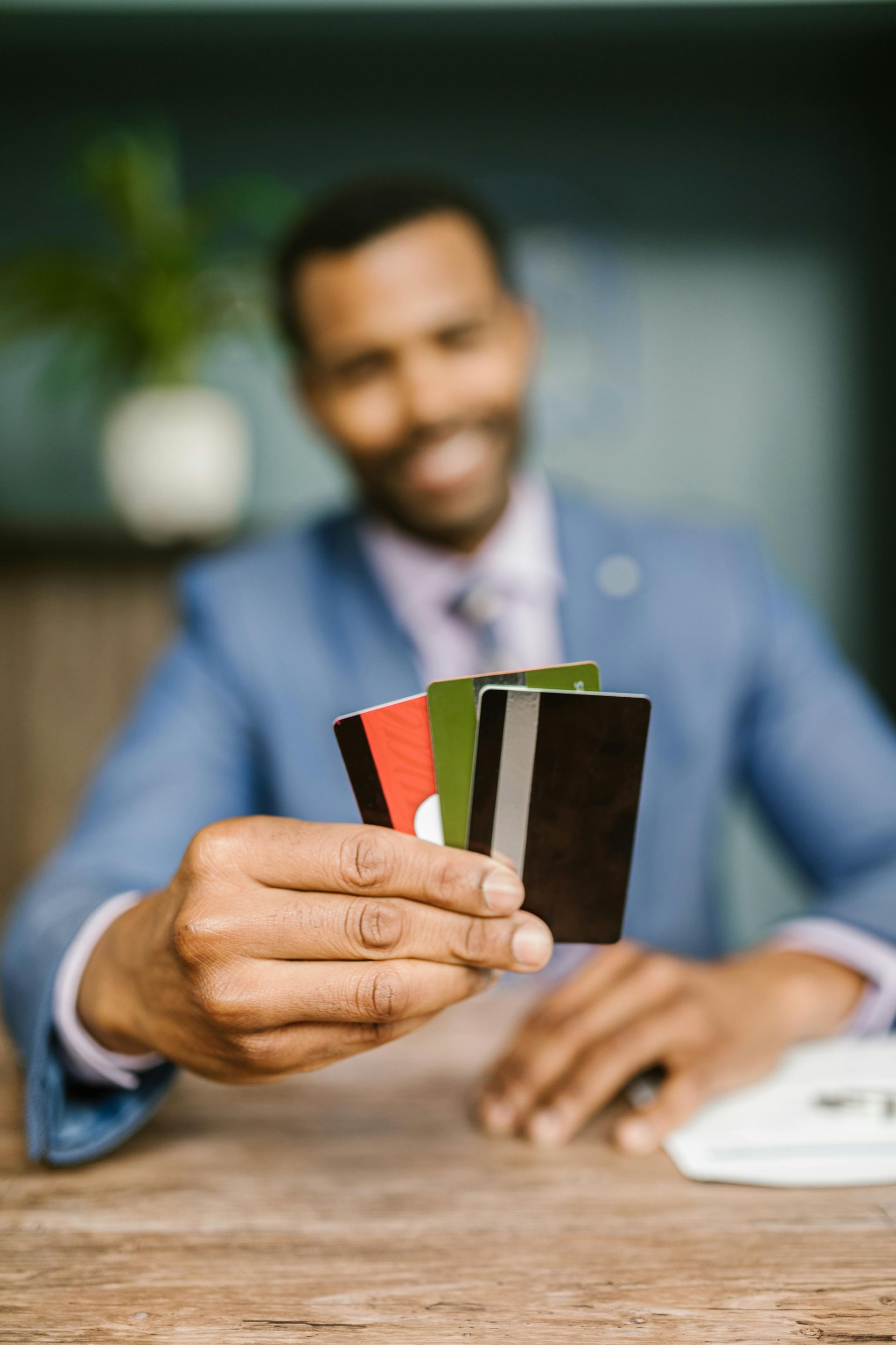 A man in a suit is holding four credit cards in his hand.