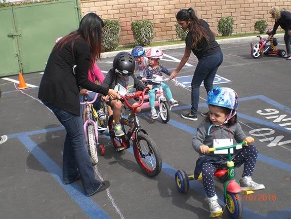 Children Riding a Bike With Volunteers — Riverside, CA — Cottonwood Montessori