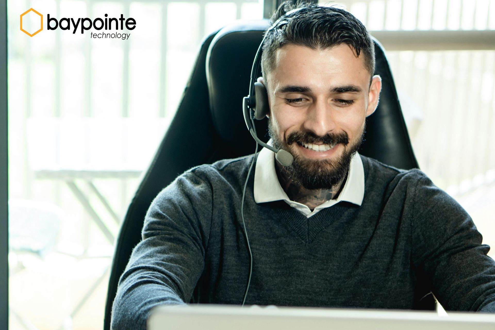 Smiling person at a desk in an office, with a Baypointe logo in the corner