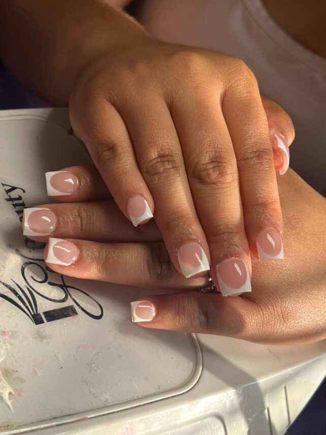 Close-up of hands showing manicured square-shaped nails with a classic white French tip design.