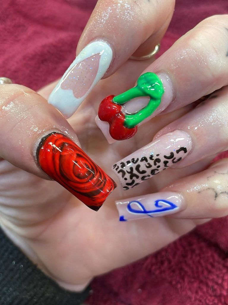 A close-up of a hand with long, square-shaped acrylic nails featuring various designs.