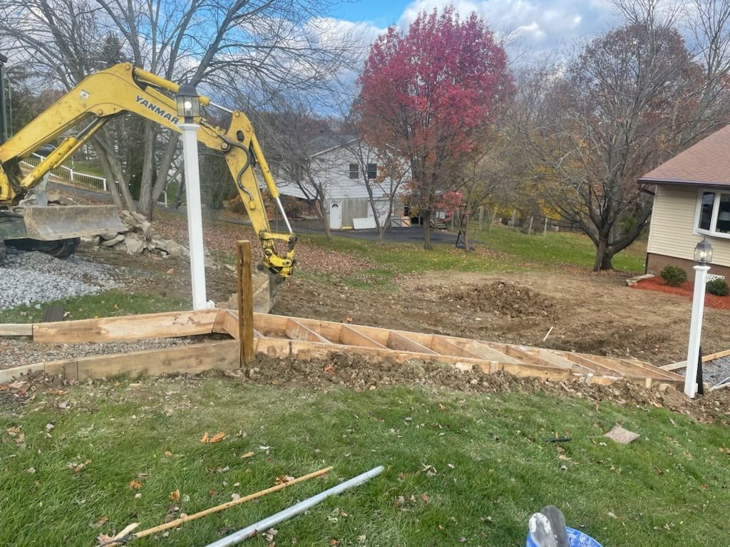 A yellow excavator is working on a fence in front of a house.