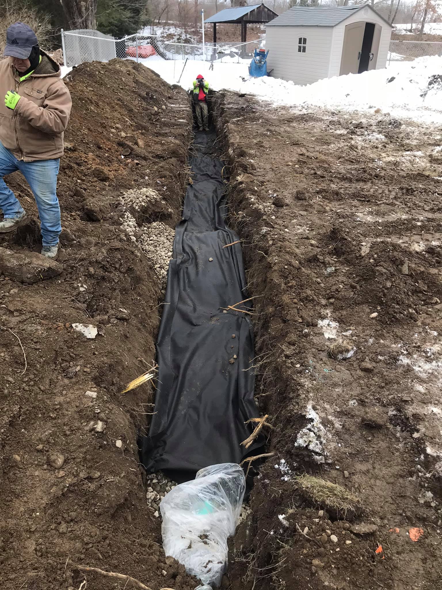 A man is standing in the dirt next to a large pile of dirt.