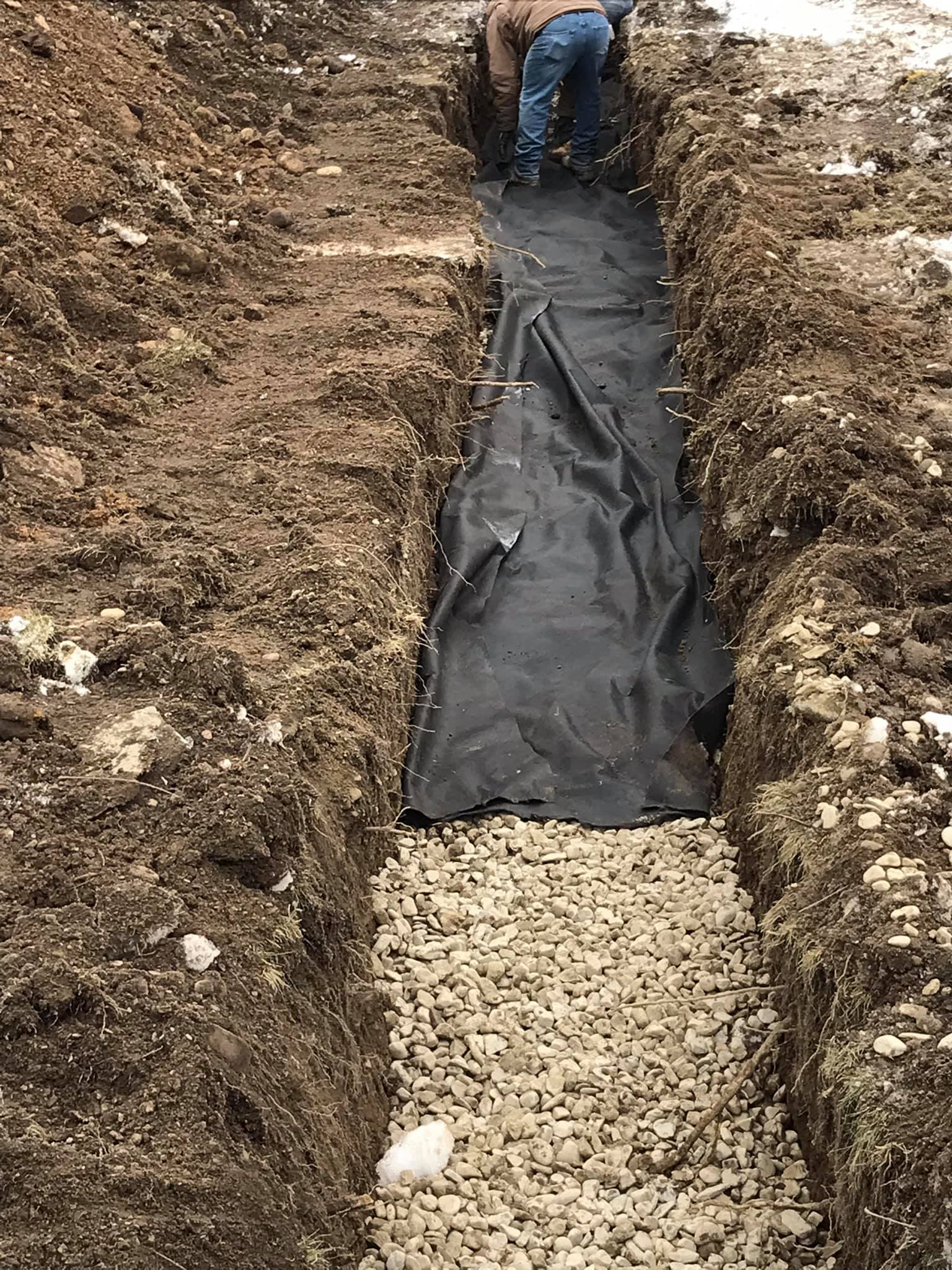 A man is digging a trench in the dirt.