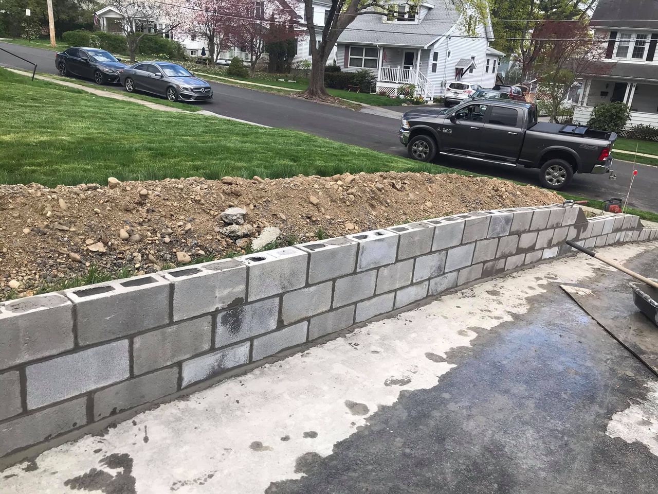A truck is parked on the side of the road next to a brick wall.