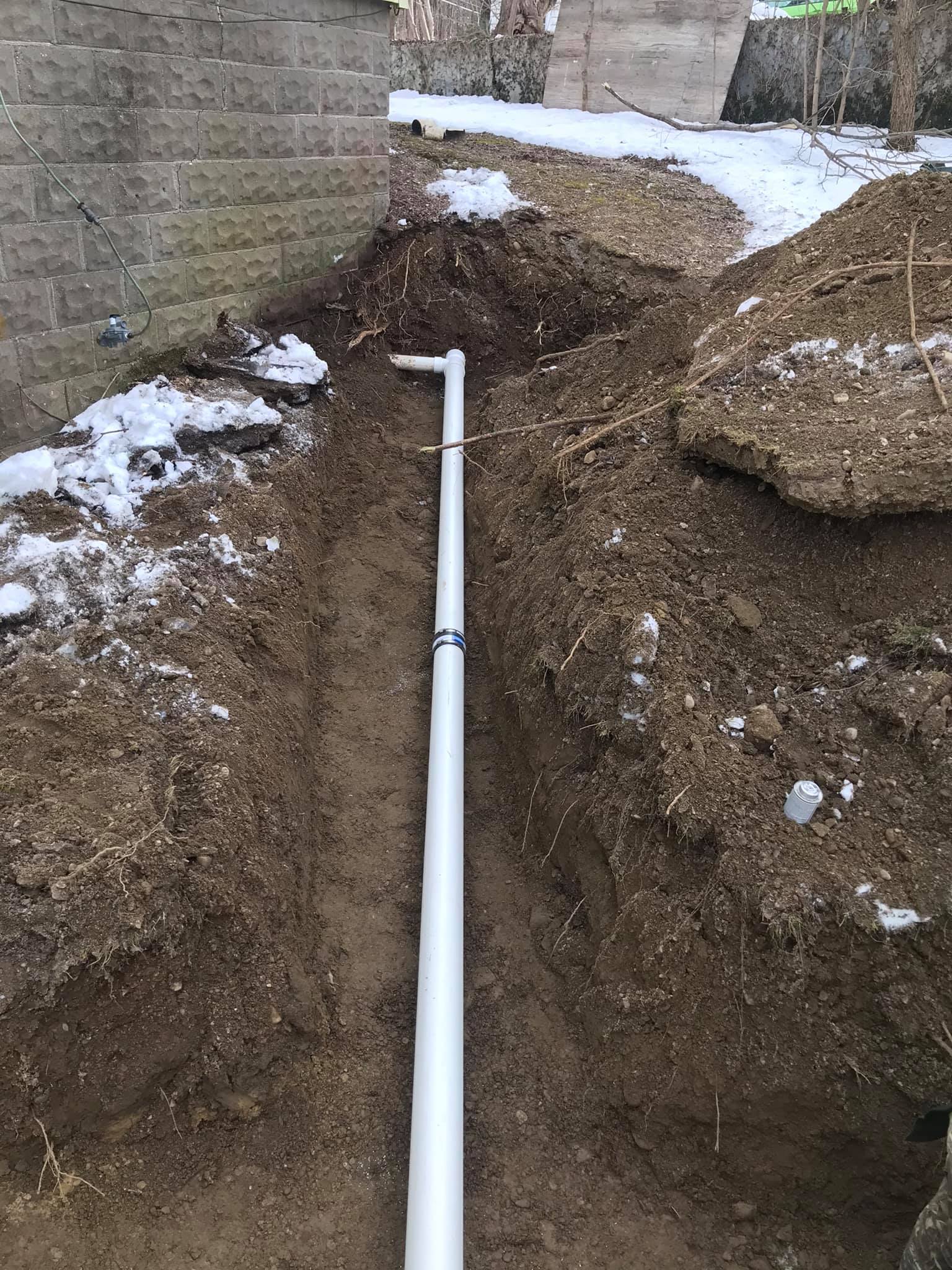 A white pipe is being installed in the dirt.