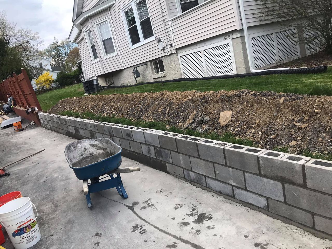 A wheelbarrow is sitting on the sidewalk next to a brick wall.