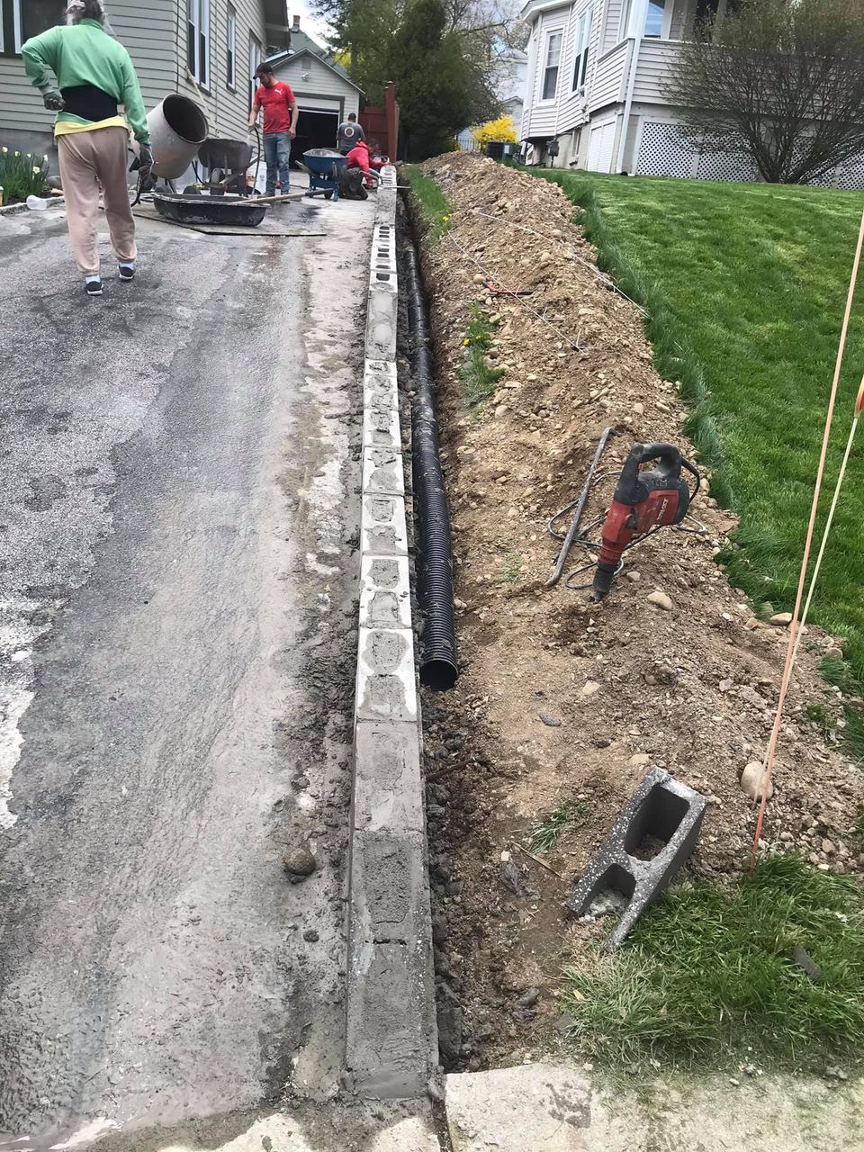 A man is walking down a road next to a pile of dirt.