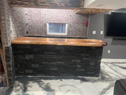 A bar in a basement with a brick wall and a wooden counter top.
