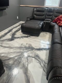 A living room with a couch and ottoman on a marble floor.