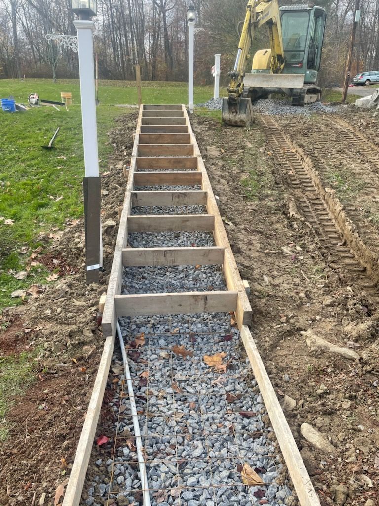 A concrete walkway is being built in a field with a bulldozer in the background.