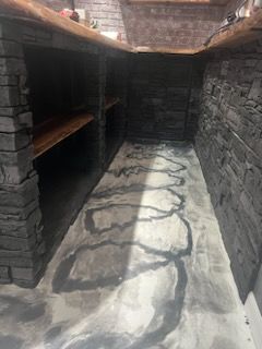 A narrow room with a brick wall and a concrete floor.