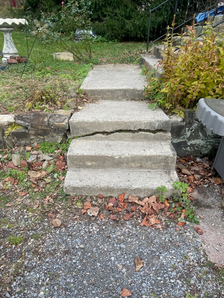 A cracked set of concrete stairs leading up to a house.