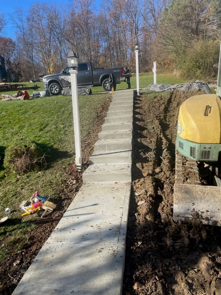 A concrete walkway is being built next to a truck and a bulldozer.