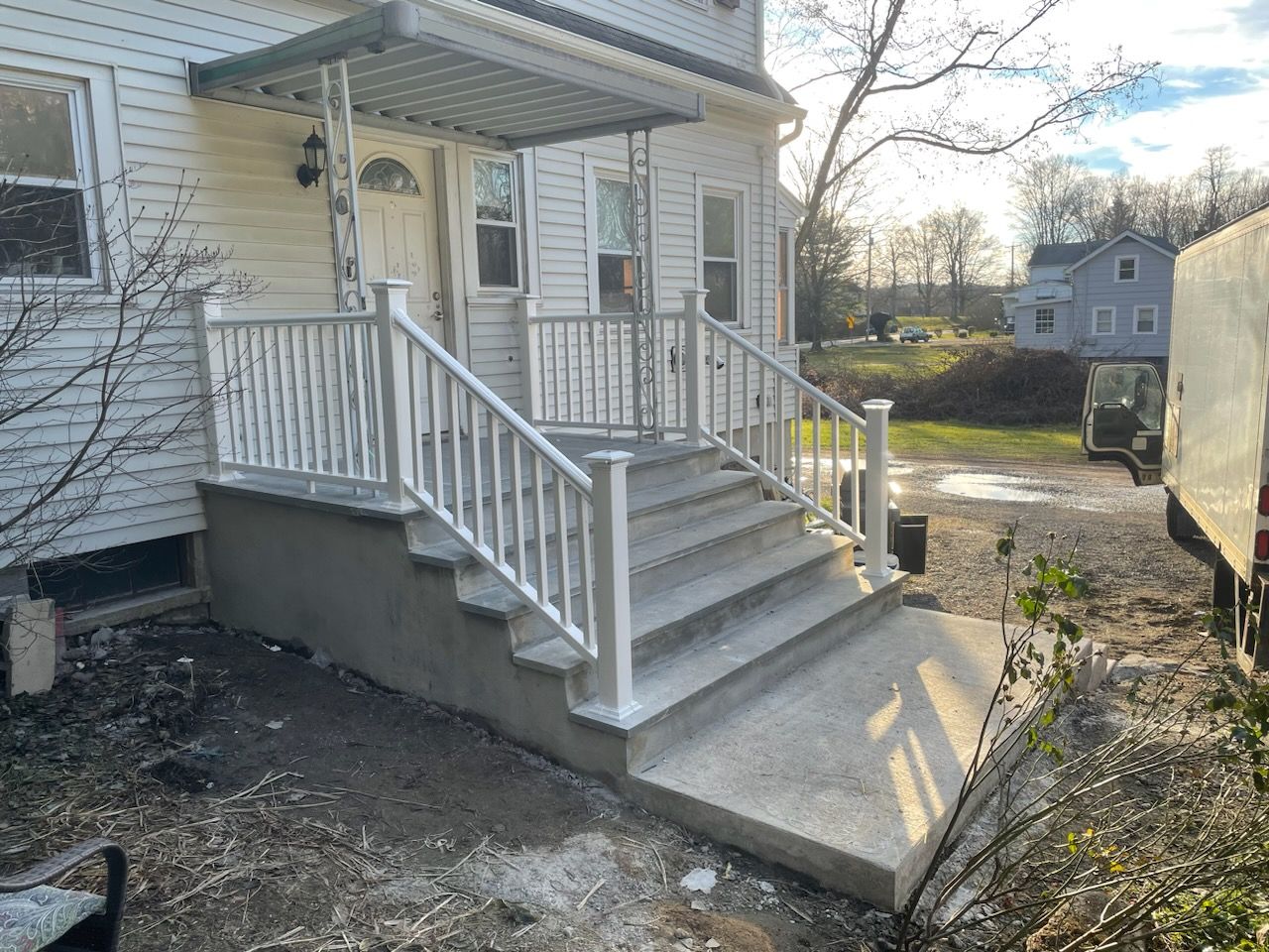 A white house with a white porch and stairs.