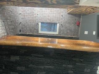 A kitchen with a wooden counter top and a brick wall.