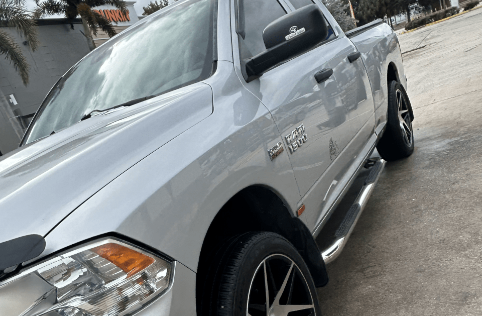 Silver Dodge Ram truck parked on a street, featuring black rims and running boards.
