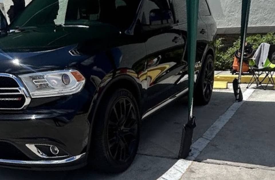 Black Dodge Durango SUV, parked. Chrome trim, black wheels. Sunny day.