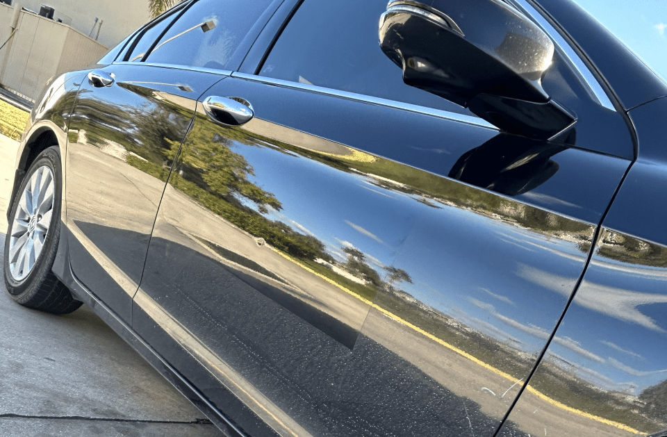 Black car parked outside, reflecting surroundings.