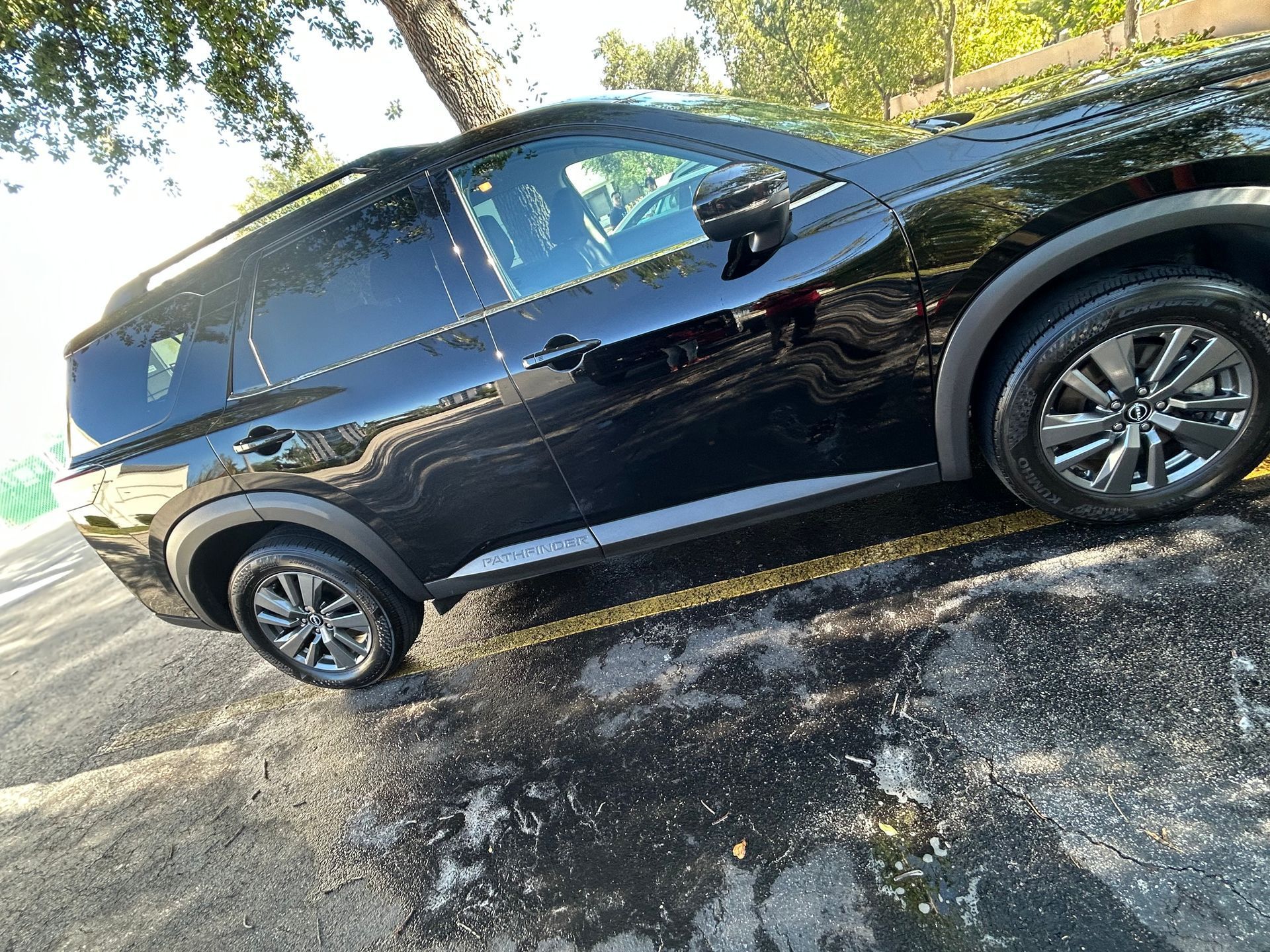 Black SUV parked on wet pavement, reflecting the vehicle.