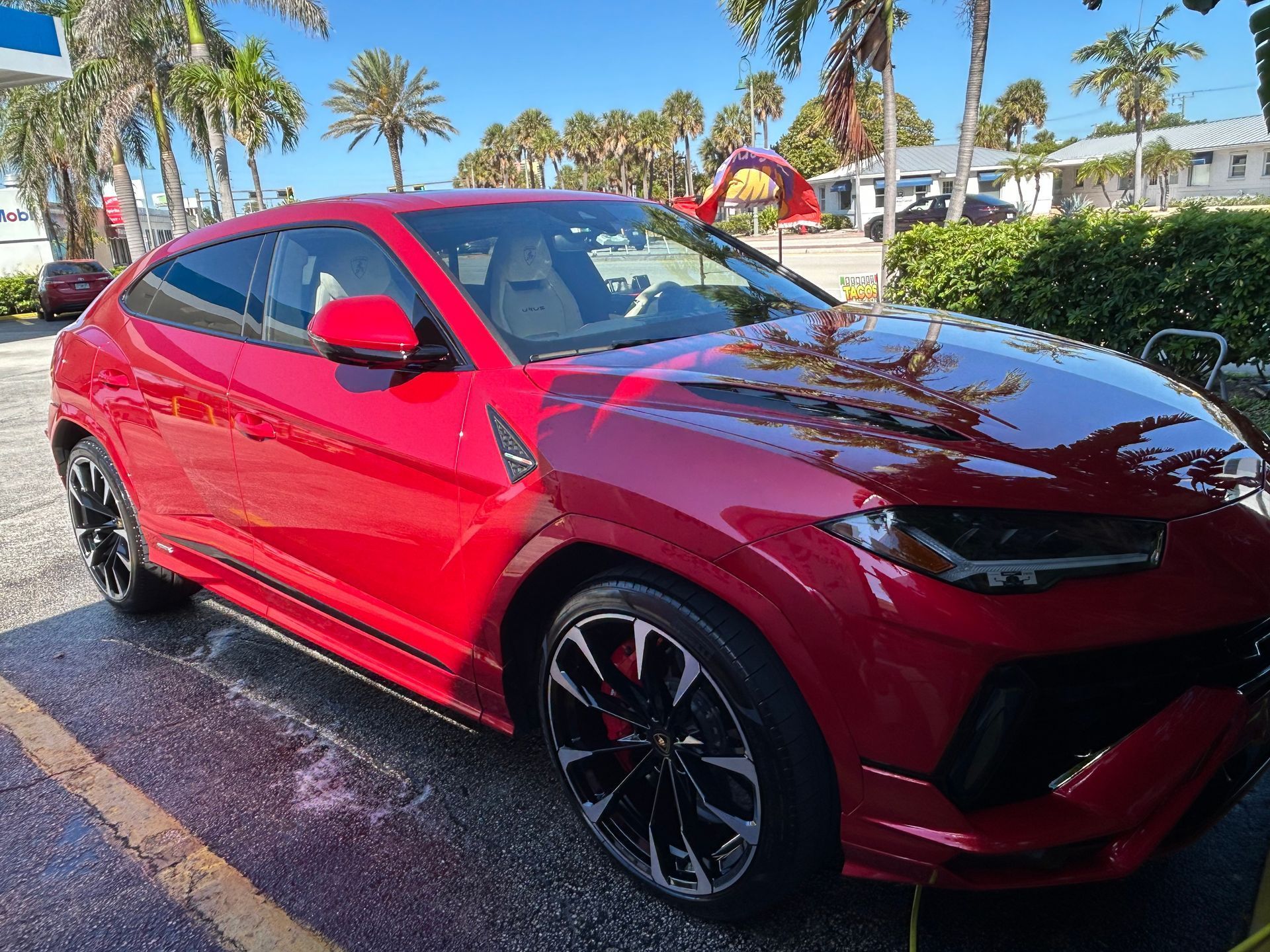 Red Lamborghini Urus SUV parked outdoors on a sunny day.