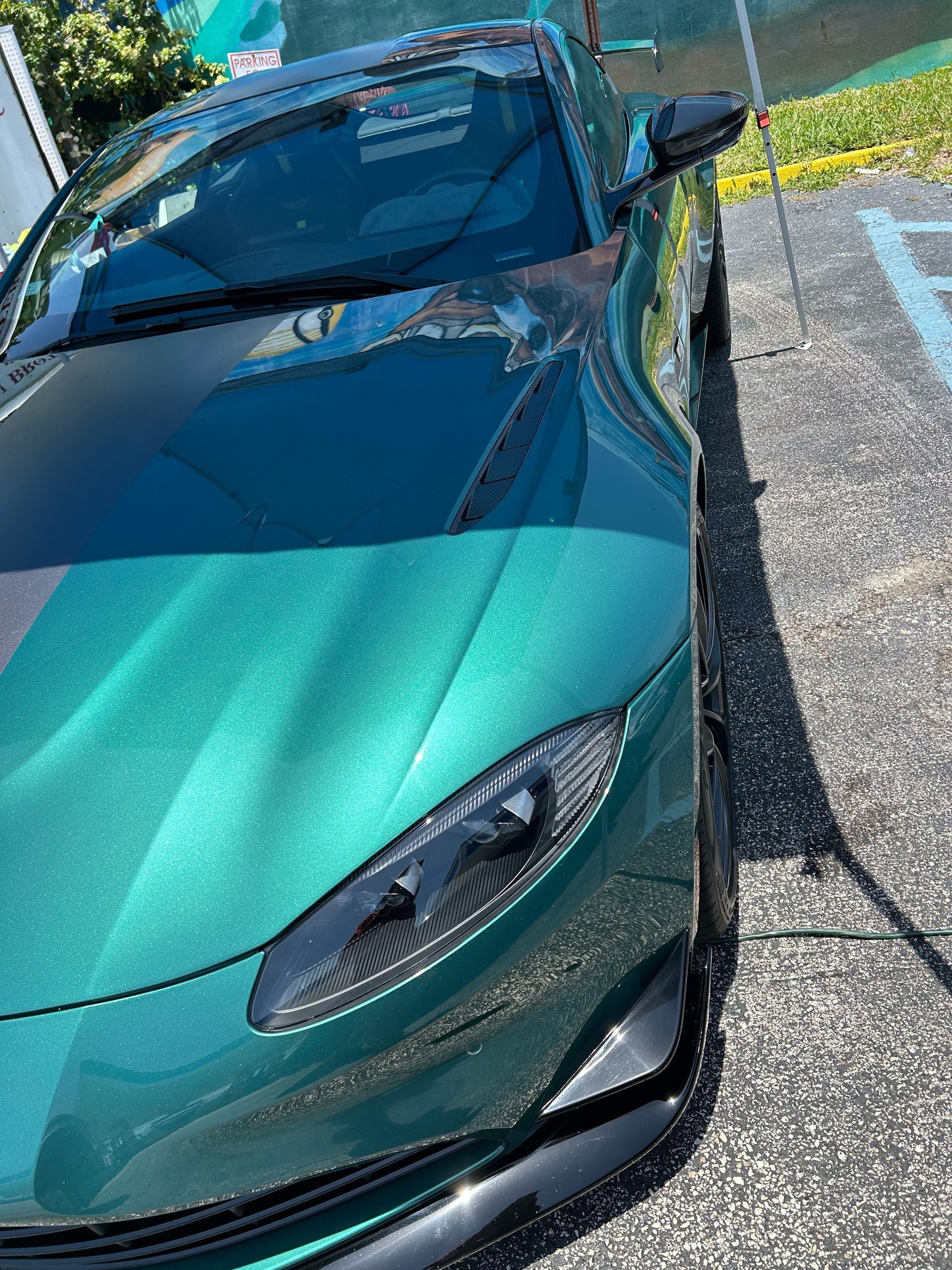 Green sports car parked in a parking lot on a sunny day.