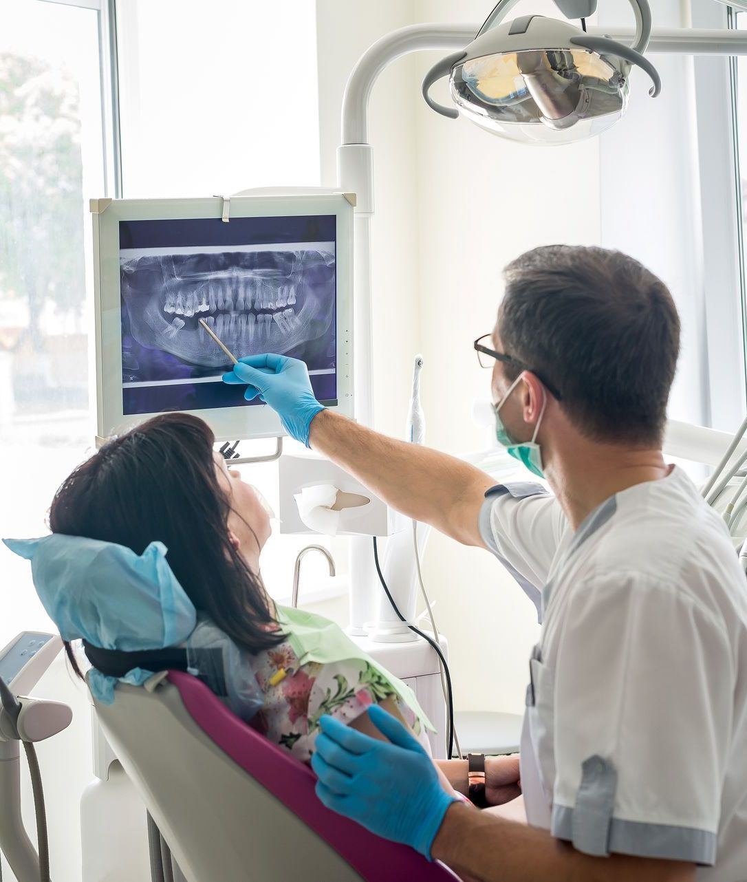 A female dentist is sitting on a dental chair in a dental office.