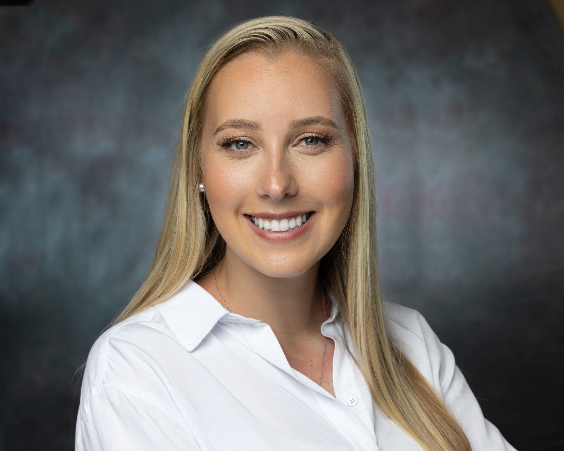 A woman in a white shirt is smiling for the camera.