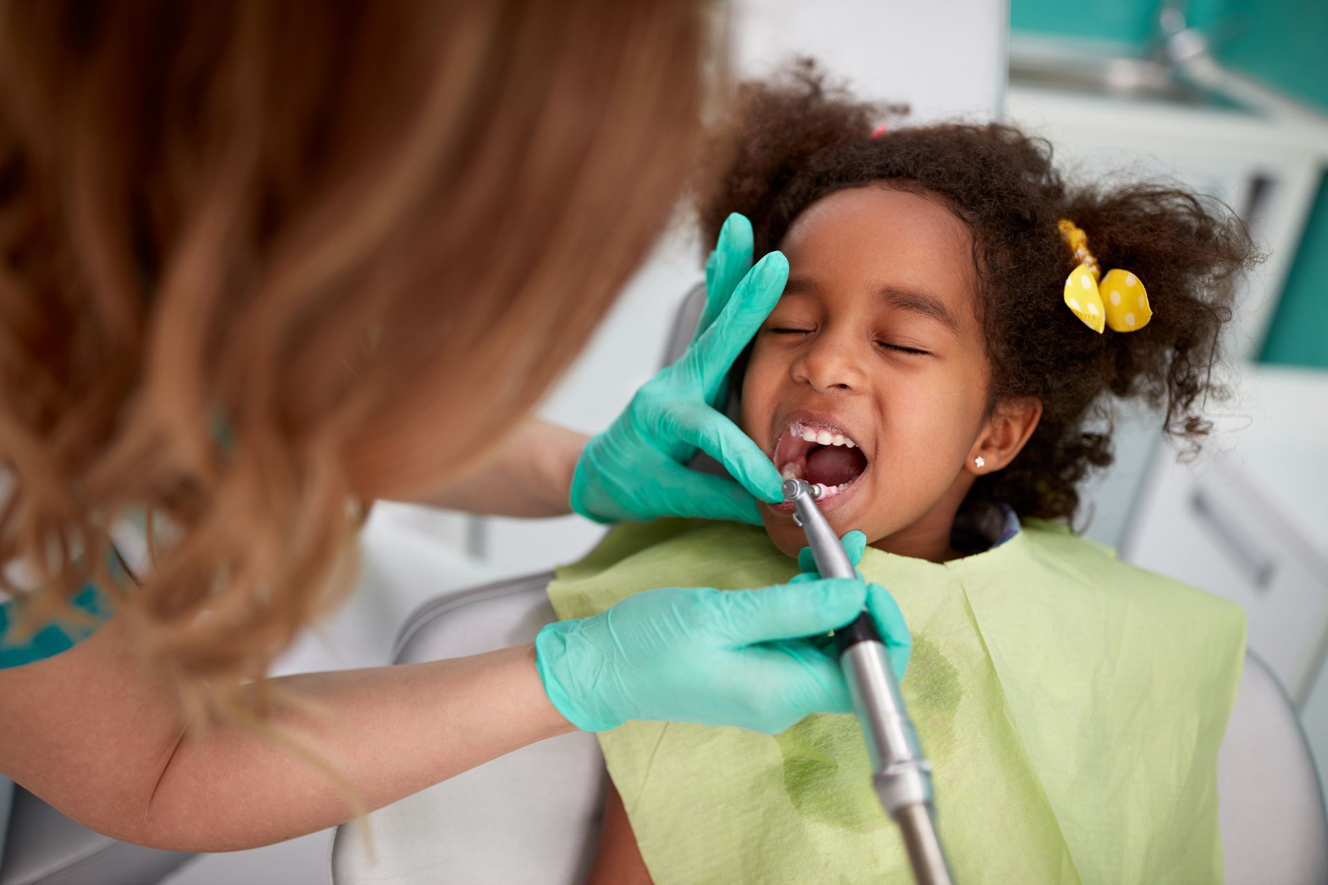 A man is sitting in a dental chair looking at his teeth in a mirror.