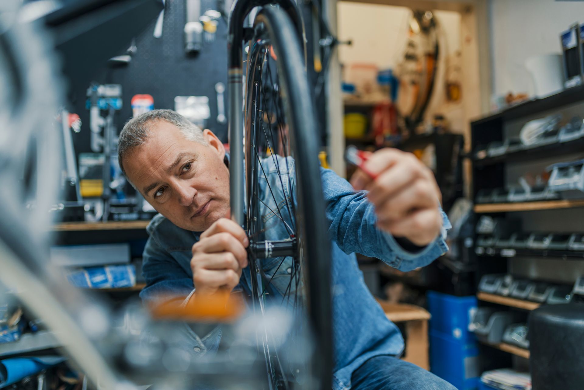 A man is fixing a bicycle wheel in a garage.