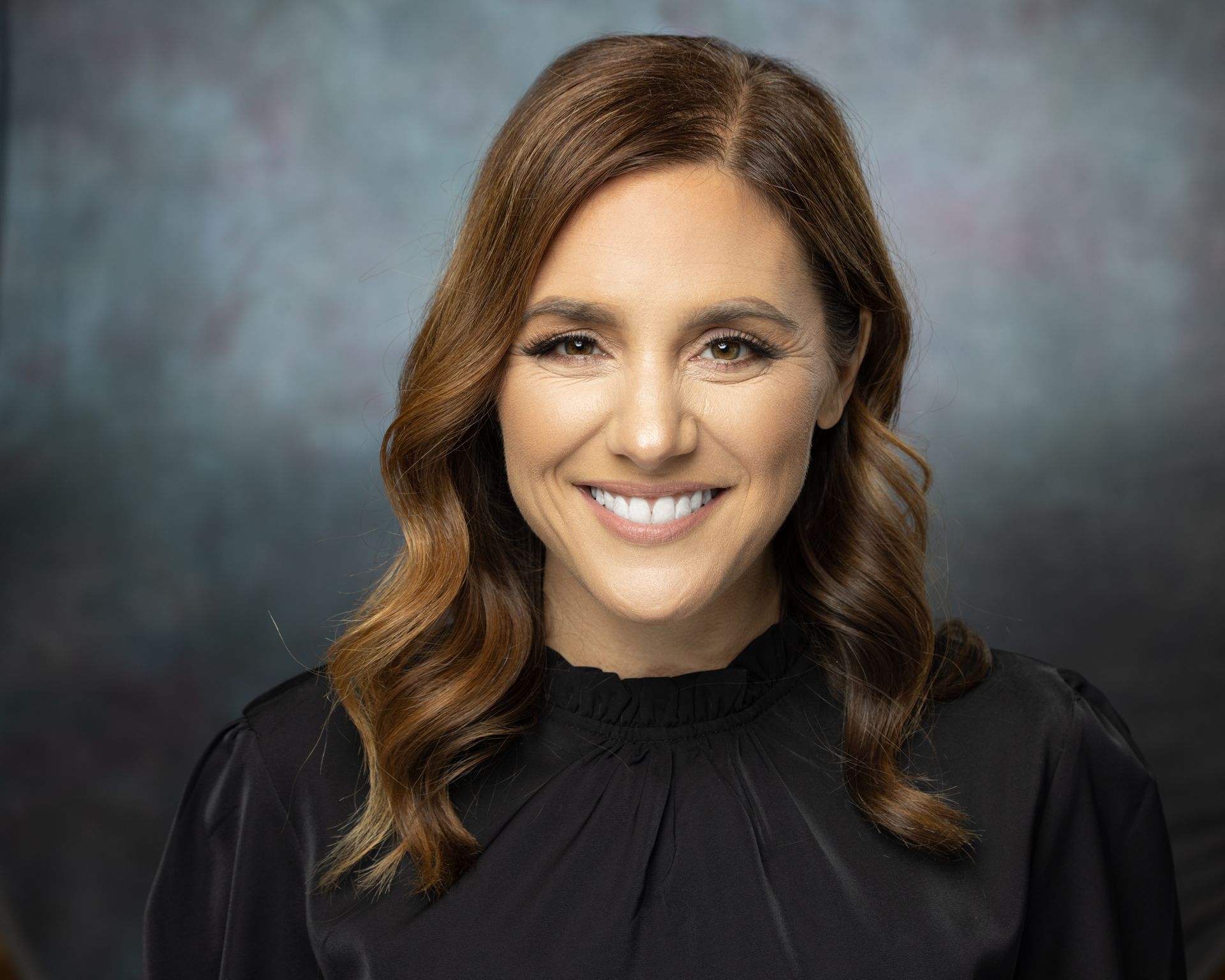 A woman in a black shirt is smiling for the camera.