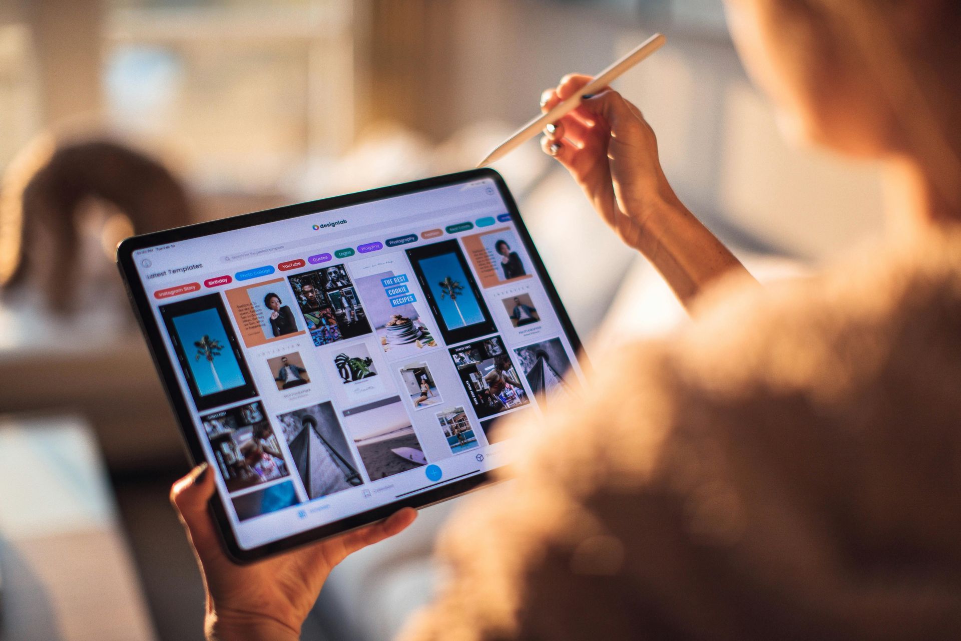 A woman is using a tablet computer with a pencil.