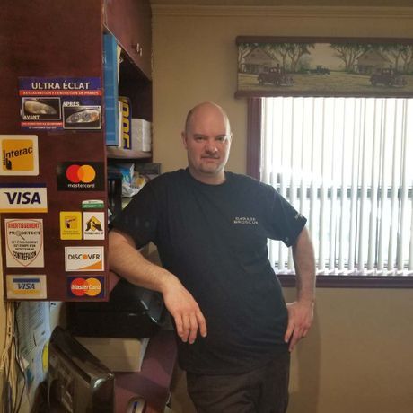 Un homme debout devant un mur avec des autocollants visa et mastercard dessus