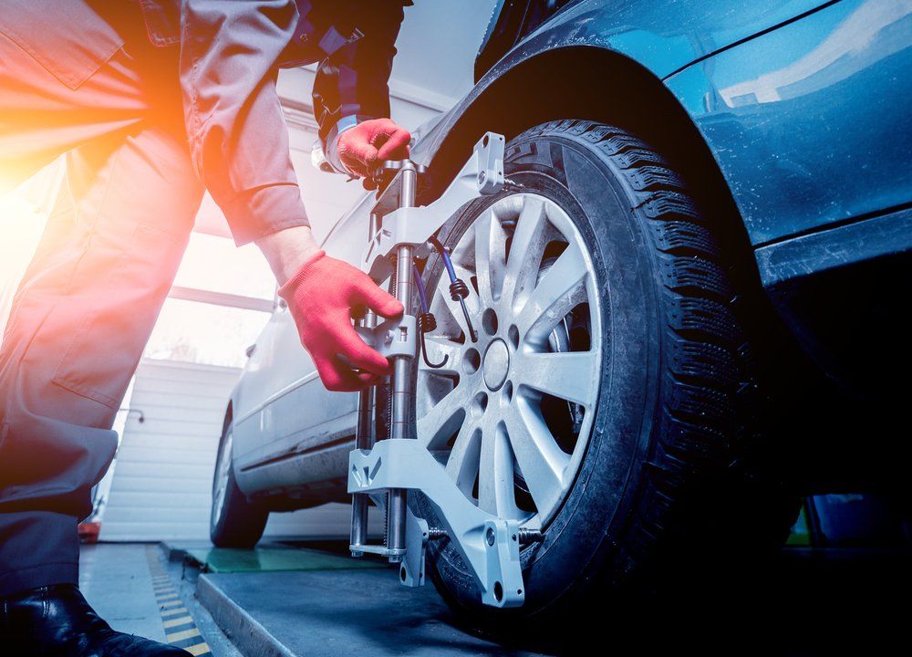 Un homme ajuste un pneu sur une voiture dans un garage.