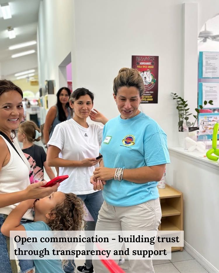 People communicating, smiling in a light-filled space. A child looks up. Text: Open communication - building trust.