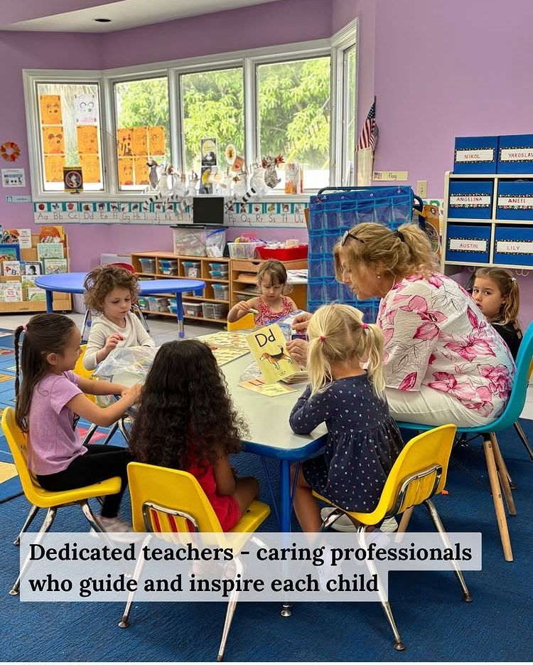 Children and teacher reading at a table in a brightly colored classroom.