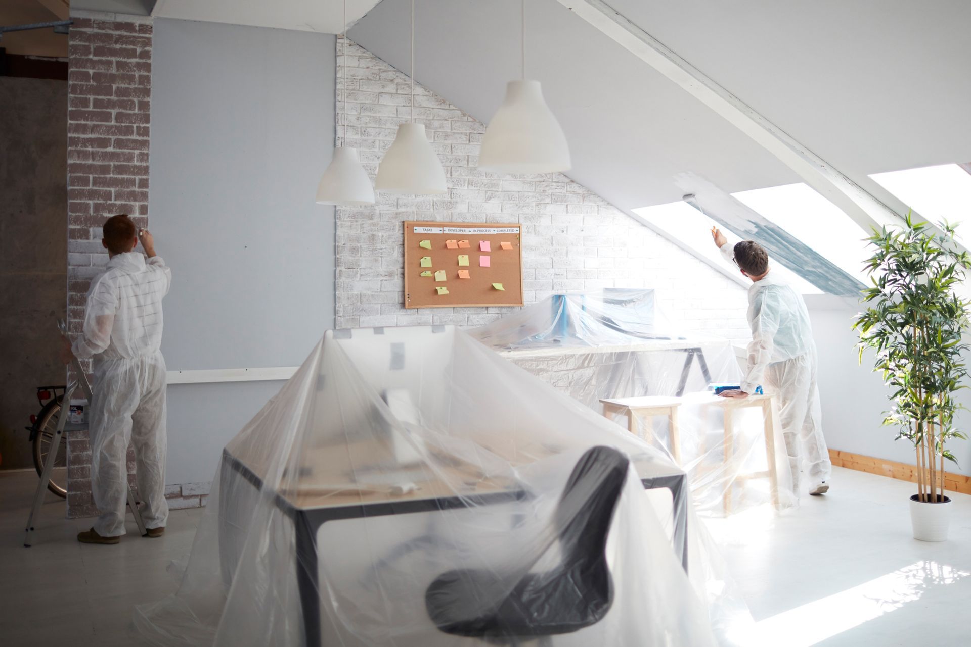 A man is painting a wall in an office.